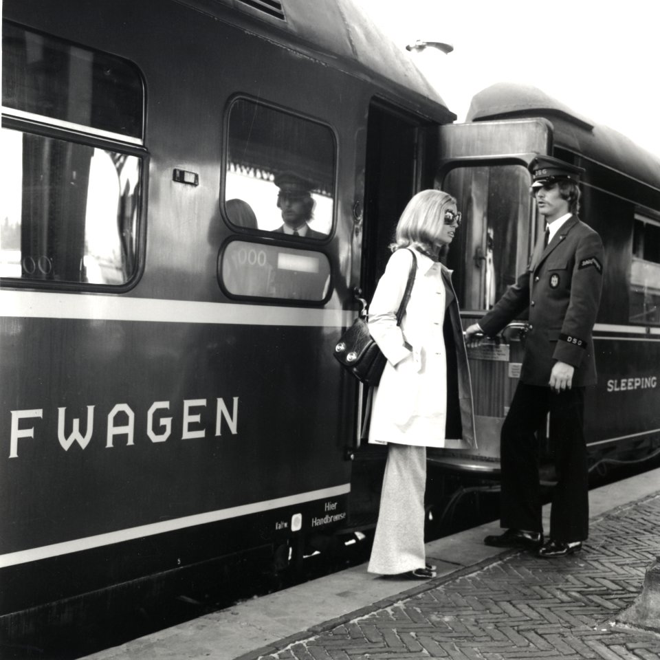 HUA-168165-Afbeelding van een treinreizigster bij een slaapwagen van Wagons-Lits in de Showtrein '72 te 's-Hertogenbosch, met rechts een steward van de D.S.G. (Deutsche Schlafwagen- und Speisewagen Gesellschaft)