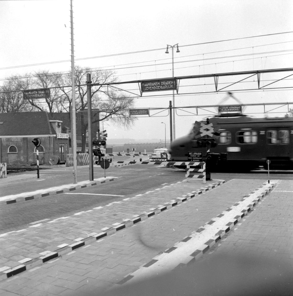 HUA-159950-Gezicht op een met AHOB s beveiligde spoorwegovergang te De Vink bij Leiden tijdens het passeren van een electrisch treinstel mat 1954 van de NS