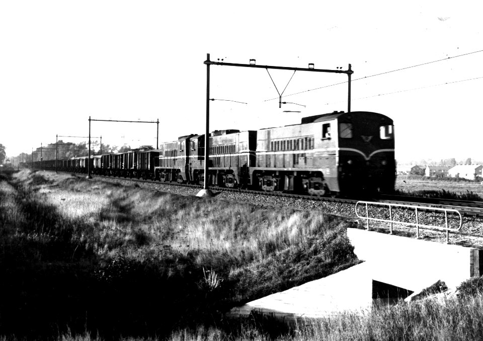 HUA-159827-Afbeelding van drie diesel-electrische locomotieven uit de serie 2200-2300 van de N.S. met een ertstrein ter hoogte van Amsterdam Watergraafsmeer