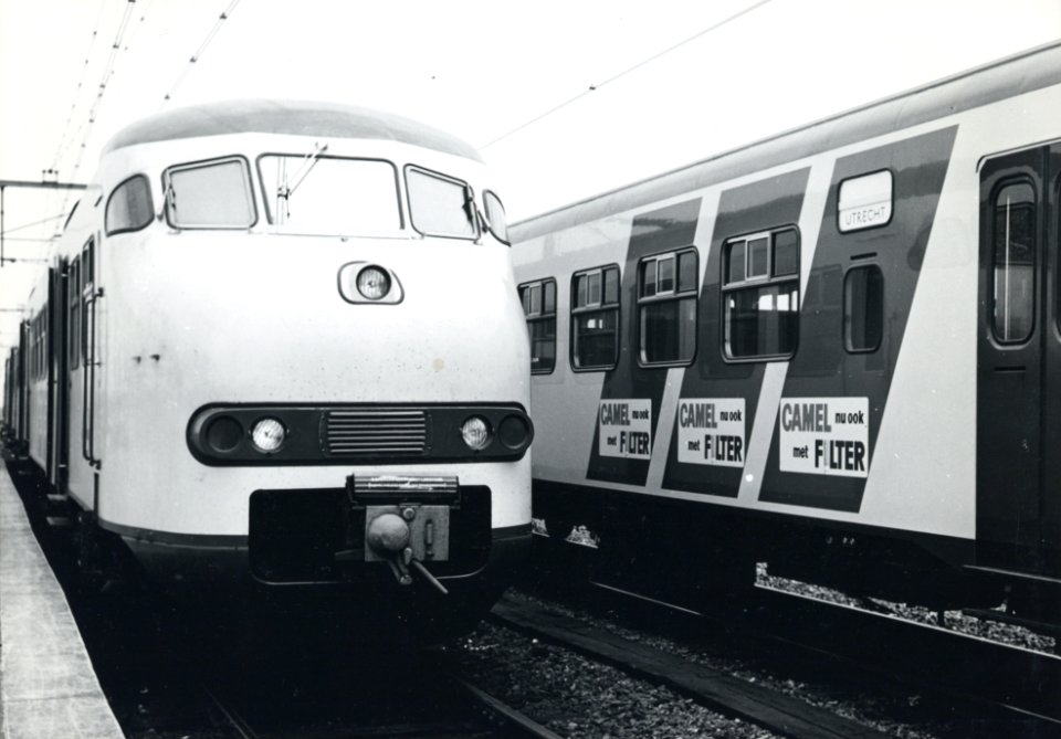 HUA-170712-Afbeelding van de introductie van de nieuwe, gele huisstijl van de electrische treinstellen mat. 1964 (plan V) van de N.S. op het traject Utrecht-Leiden, met rechts de blauwe, diagonale reclamebanden 