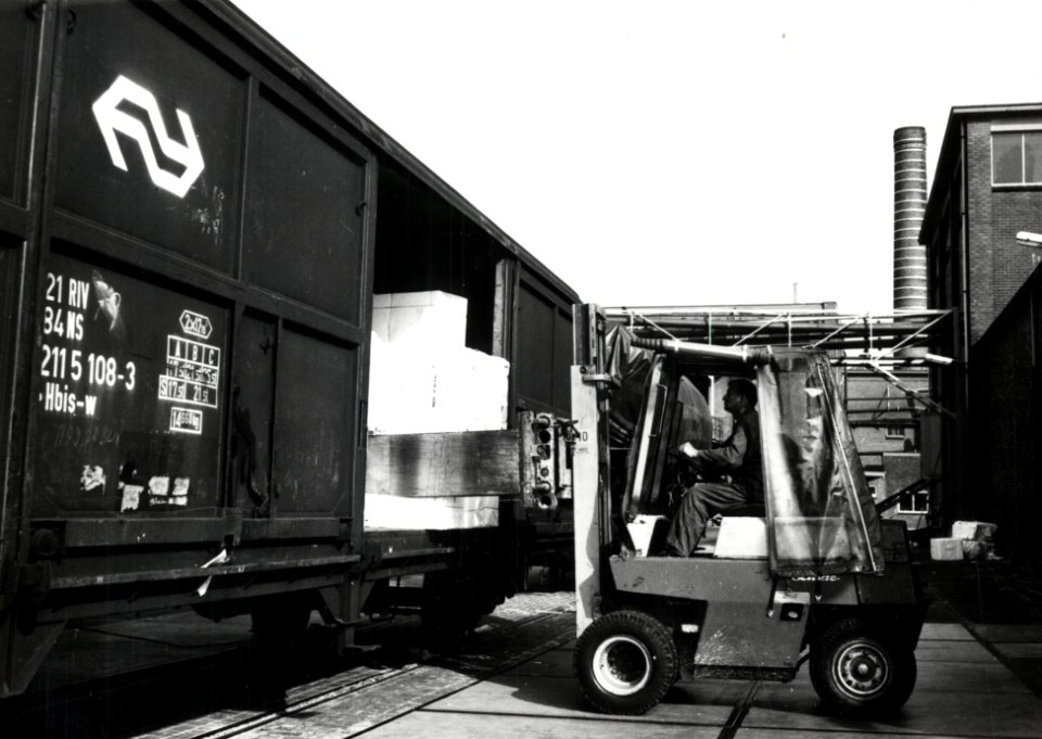 HUA-171226-Afbeelding van het beladen van goederenwagens schuifwandwagen type Hbis w van de NS met behulp van een heftruck met papier te Eerbeek