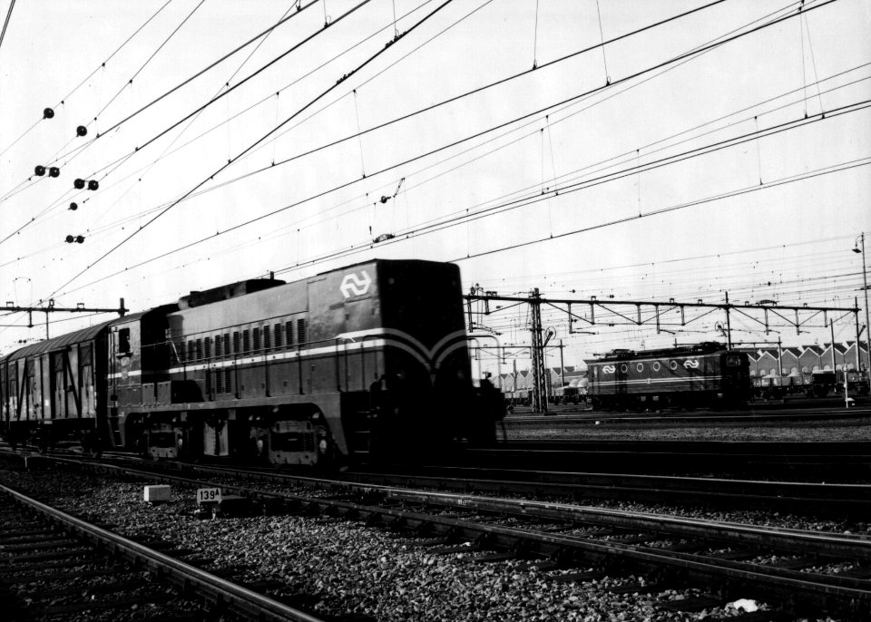 HUA-159889-Afbeelding van een diesel electrische locomotief uit de serie 2200 2300 van de NS met een goederentrein te Amersfoort Rechts de electrische locomotief