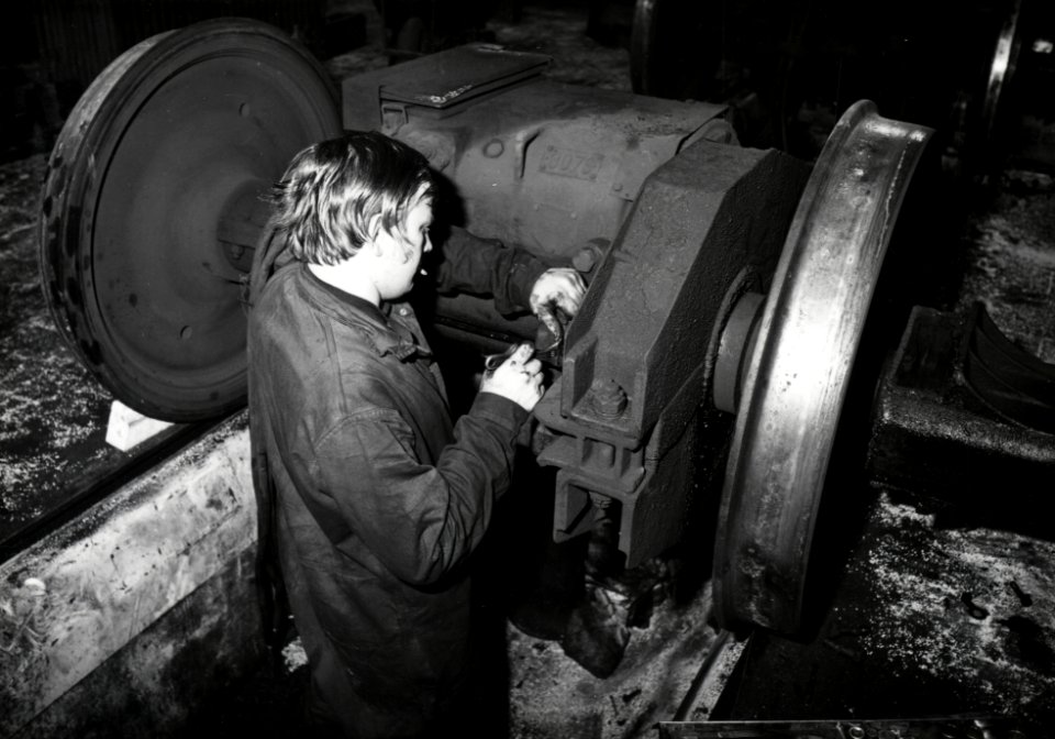 HUA-169948-Afbeelding van een monteur van de hoofdwerkplaats van de N.S. te Tilburg tijdens werkzaamheden aan een wielstel met een electromotor