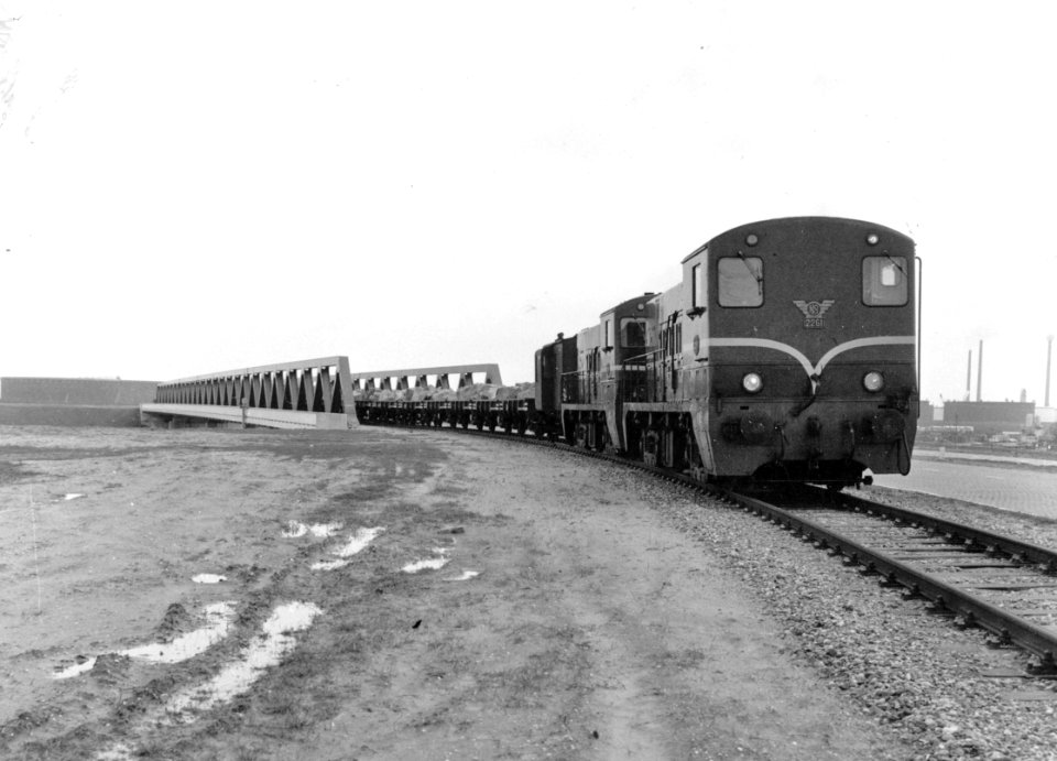 HUA-171030-Afbeelding van een goederentrein met stenen, getrokken door twee diesel-electrische locomotieven uit de serie 2200-2300 (voorop de 2261) van de N.S. op de Dintelhavenbrug ten behoeve van de aanleg van