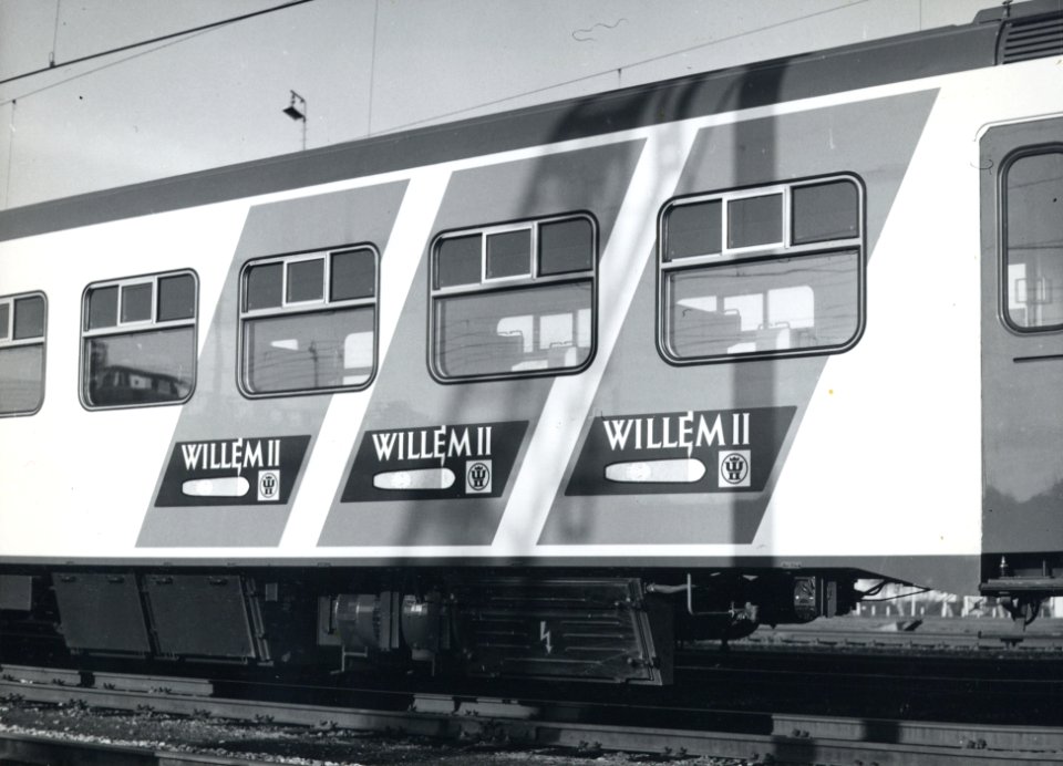 HUA-170705-Afbeelding de blauwe, diagonale reclamebanden met reclame voor Willem II op de zijwand van het electrische treinstel nr. 431 (Plan V, mat. 1964) van de N.S. tijdens de presentatie van de nieuwe, gele 