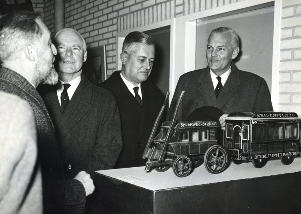 HUA-171130-Afbeelding van president-directeur ir. J. Lohmann van de N.S. (geflankeerd door de burgemeesters van Zeist en Driebergen-Rijsenburg) bij een model van een diligence en een oude tram tijdens de opening