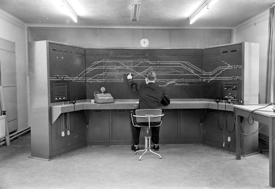 HUA-159684-Interieur van het seinhuis van de N.S. te Eindhoven, met de treindienstleider bij het NX-bedieningstableau