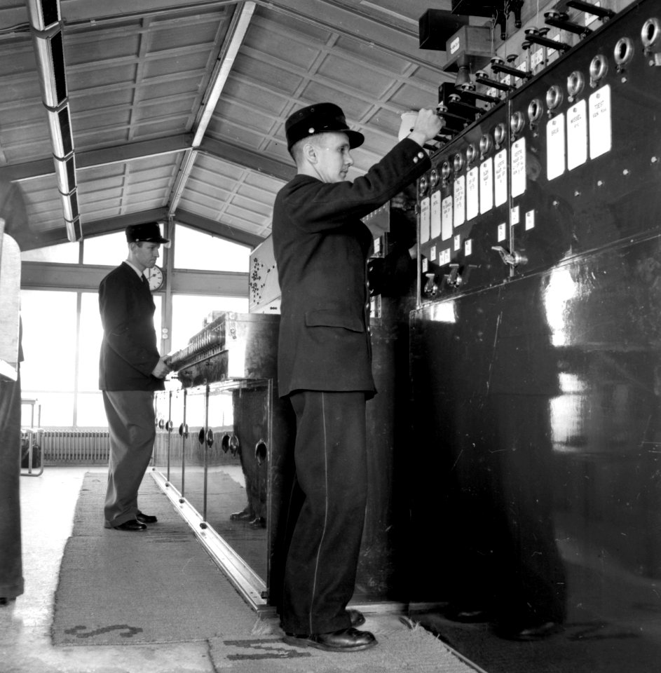 HUA-159794-Afbeelding van de seinhuiswachters bij het bloktoestel in het seinhuis van de NS te Zutphen