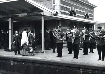 HUA-171156-Afbeelding van het muziekkorps van de Delftse Politiemuziekvereniging Excelsior op het perron van het N.S.-station Delft tijdens de feestelijke opening van het spoorviaduct door de stad