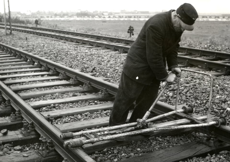 HUA-168988-Afbeelding van een wegwerker van de NS tijdens het regelen van de spoorwijdte op het baanvak te Berkel