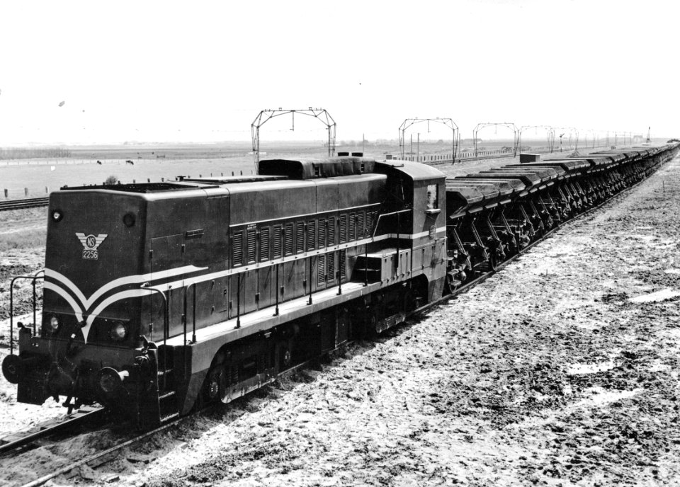 HUA-171022-Afbeelding van de diesel-electrische locomotief nr. 2256 (serie 2200-2300) van de N.S. met een zandtrein te Hoek van Holland ten behoeve van de versterking van de zeewering bij Ter Heijde