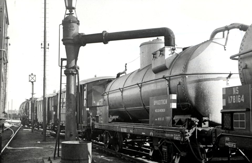 HUA-169055-Afbeelding van een waterkolom van de NS tijdens het nemen van water voor één van de ketelwagens van de sproeitrein onkruidbestijdingstrein 