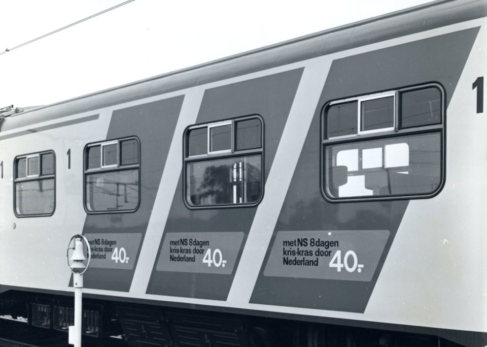 HUA-170709-Afbeelding van de blauwe diagonale reclamebanden met reclame voor het 8 daagse abonnement van NS op de zijwand van een electrisch treinstel plan V mat