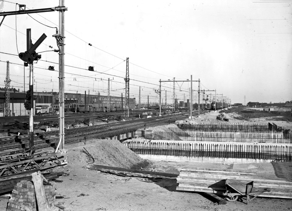 HUA-169132-Gezicht op de spoorwegwerken te Leiden, met op de voorgrond de in aanleg zijnde perrontunnel en de plek van het toekomstige nieuwe stationsgebouw. Links op de achtergrond de remise van de N.Z.H