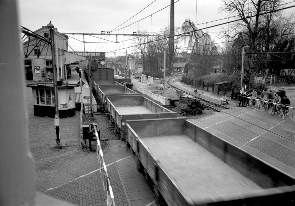 HUA-168891-Gezicht op de spoorwegovergang bij het N.S.-station Driebergen-Zeist te Driebergen-Rijsenburg, vanaf het seinhuis, tijdens de passage van een goederentrein
