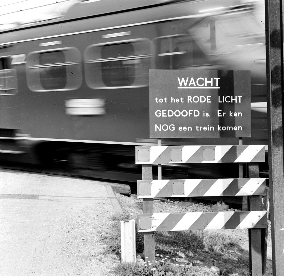 HUA-167637-Afbeelding van het bord "Wacht tot het rode licht gedoofd is. Er kan nog een trein komen" bij de spoorwegovergang in de spoorlijn Lage Zwaluwe-Breda, nabij Zevenbergschenhoek