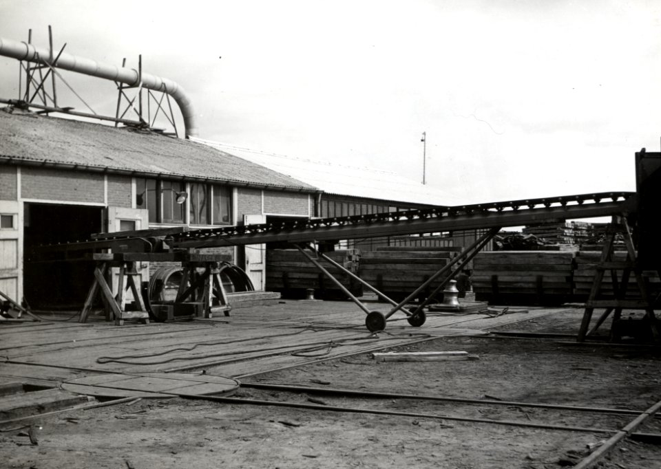 HUA-168960-Afbeelding van een transportband voor het vervoer van dwarsliggers op het terrein van het Houtbereidingsbedrijf HBI van de NS te Dordrecht