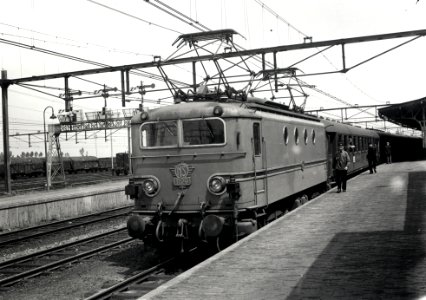 HUA-167993-Afbeelding van de electrische locomotief nr. 1129 (serie 1100) van de N.S. met een trein langs het perron van het N.S.-station Roosendaal te Roosendaal