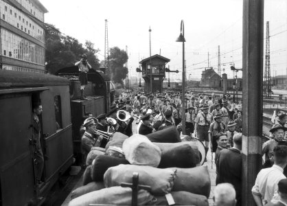 HUA-167546-Afbeelding van het vertrek van een groep padvinders per trein naar de Jamboree te Oostenrijk op het perron van het N.S.-station Utrecht C.S. te Utrecht, met op de voorgrond een harmonieorkest, links e