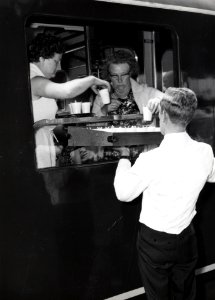 HUA-168834-Afbeelding van het uitdelen van koffie aan een groep bejaarden in de extra trein, bestaande uit rijtuigen plan D van de N.S., voor de reis van "Ouden van Dagen" op het N.S.-station Naarden-Bussum te B