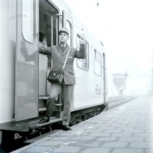 HUA-167731-Afbeelding van een conducteur tijdens het geven van het vertreksein voor een trein op het N.S.-station Utrecht C.S. te Utrecht