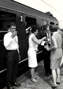 HUA-168835-Afbeelding van het uitdelen van koffie aan een groep bejaarden in de extra trein, bestaande uit rijtuigen plan D van de N.S., voor de reis van "Ouden van Dagen" op het N.S.-station Naarden-Bussum te B
