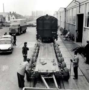 HUA-168092-Afbeelding van het vervoer van een goederenwagen van de N.S. op een oplegger van een vrachtauto ("wagon trailer" of "rolwagenvervoer") te Eindhoven