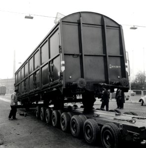 HUA-168098-Afbeelding van het vervoer van een goederenwagen van de N.S. op een oplegger van een vrachtauto ("wagon trailer" of "rolwagenvervoer") te Eindhoven