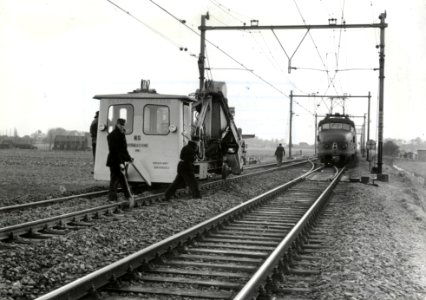 HUA-169660-Afbeelding van de hormachine van de N.S. tijdens onderhoudswerkzaamheden aan de spoorlijn te Heerhugowaard, met rechts een electrisch treinstel mat. 1954 (plan F)
