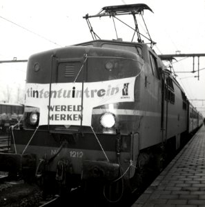 HUA-168310-Afbeelding van de electrische locomotief nr 1212 serie 1200 van de NS met de Tintentuintrein langs het perron van het NS station Lage Zwaluwe te Zeven