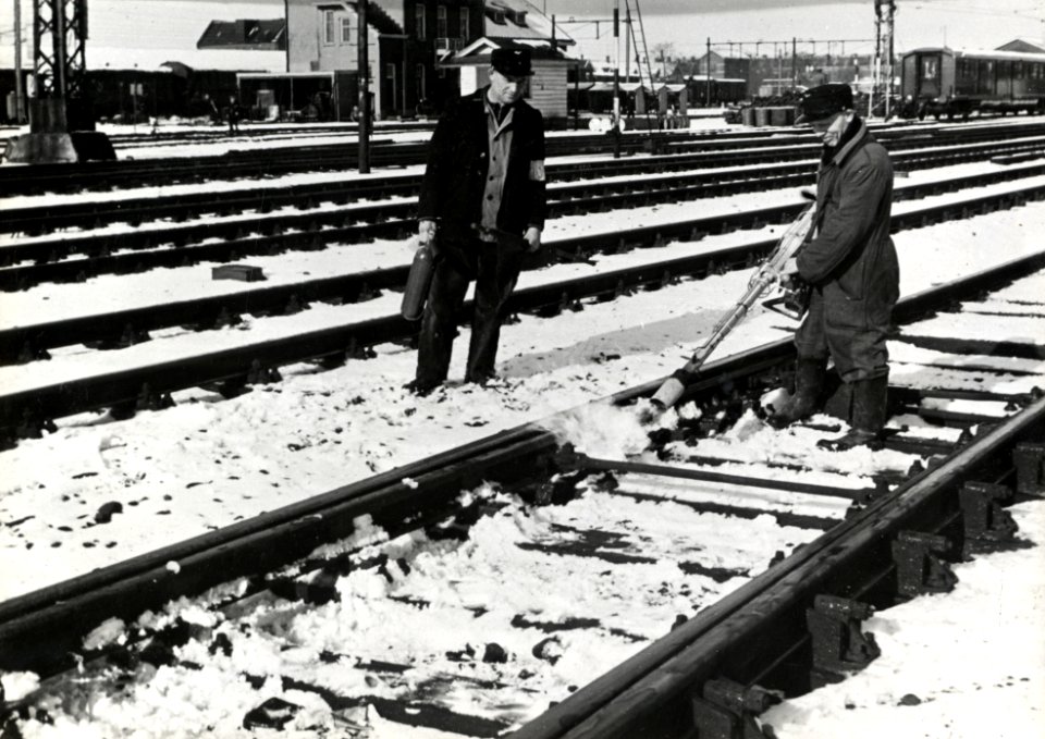 HUA-169541-Afbeelding van twee wegwerkers van de N.S. tijdens het ontdooien van een vastgevroren wissel op het emplacement van het N.S.-station Utrecht C.S. te Utrecht