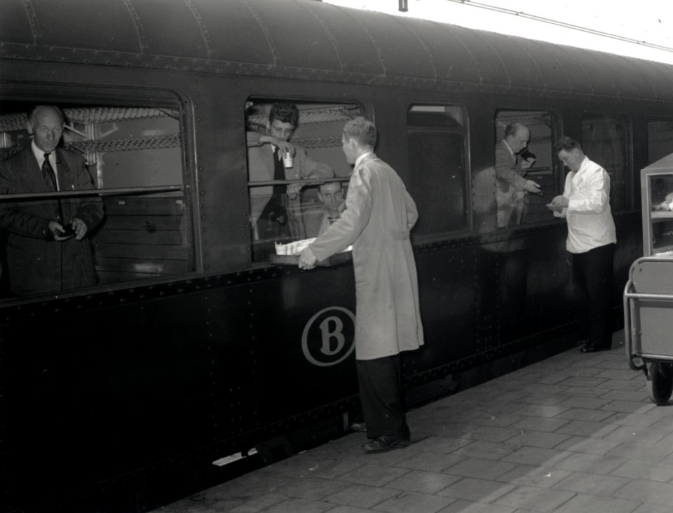 HUA-167963-Afbeelding van het verkopen van koffie aan treinreizgers in een Belgische trein op het perron van het N.S.-station Roosendaal te Roosendaal