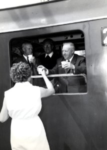 HUA-168829-Afbeelding van het uitdelen van koffie aan een groep bejaarden in de extra trein, bestaande uit rijtuigen plan D van de N.S., voor de reis van "Ouden van Dagen" op het N.S.-station Naarden-Bussum te B