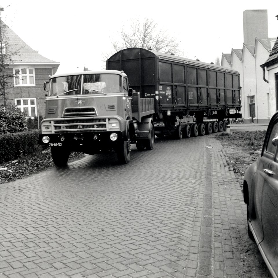 HUA-168101-Afbeelding van het vervoer van een goederenwagen van de N.S. op een oplegger van een vrachtauto ("wagon trailer" of "rolwagenvervoer") te Eindhoven