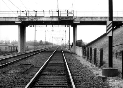 HUA-169485-Gezicht op de spoorlijn tussen Nijkerk en Amersfoort, met bakens en een voorsein ter hoogte van km. 25.4, uit het noordoosten. Op de voorgrond het viaduct van Rijksweg 1