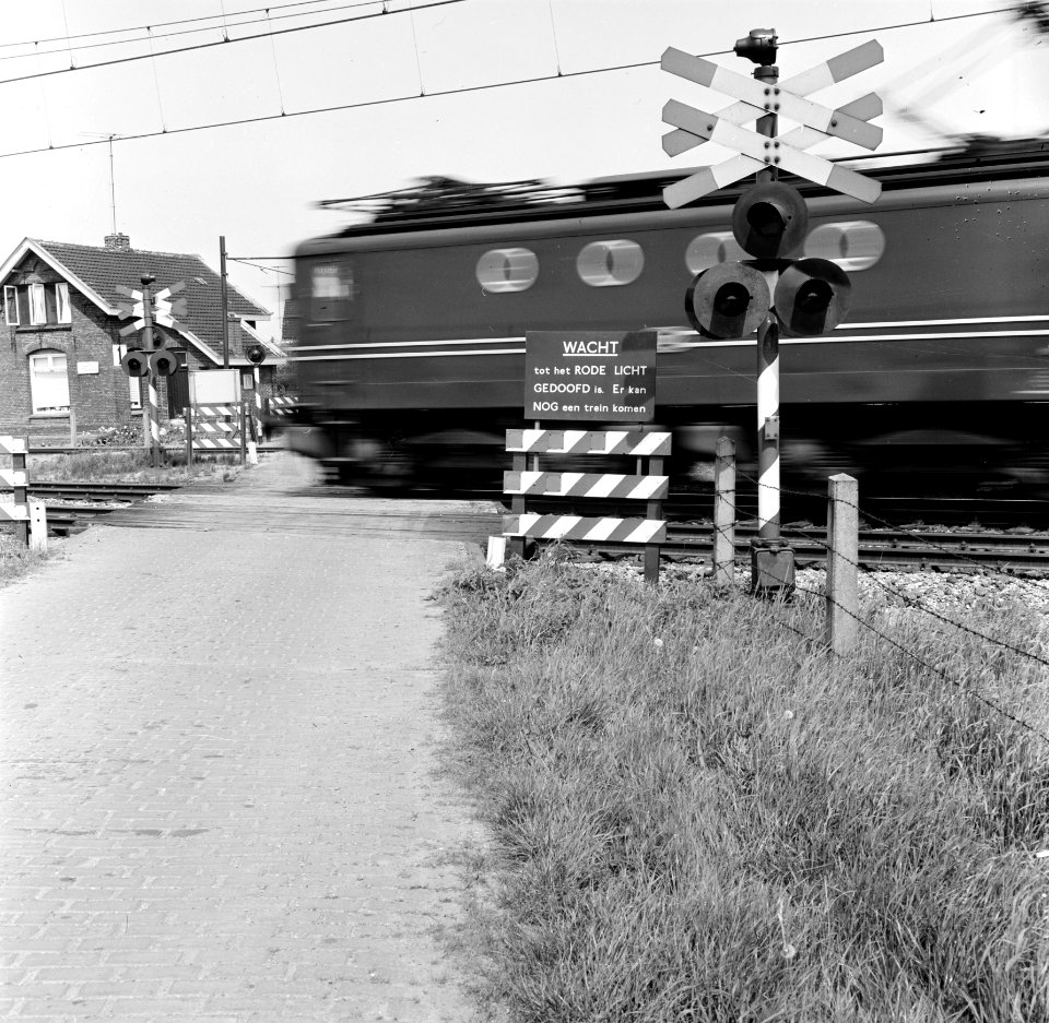 HUA-167633-De spoorwegovergang in de spoorlijn Lage Zwaluwe-Breda, nabij Zevenbergschenhoek, met een voorbijrijdende trein en links op de achtergrond de wachterswoning nr. 1 aan de spoorlijn Lage Zwaluwe - 's-Hertogenbosch