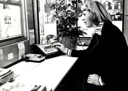 HUA-169313-Afbeelding van een informatrice met telecominstallatie in de hal van het N.S.-station Den Haag C.S. te Den Haag