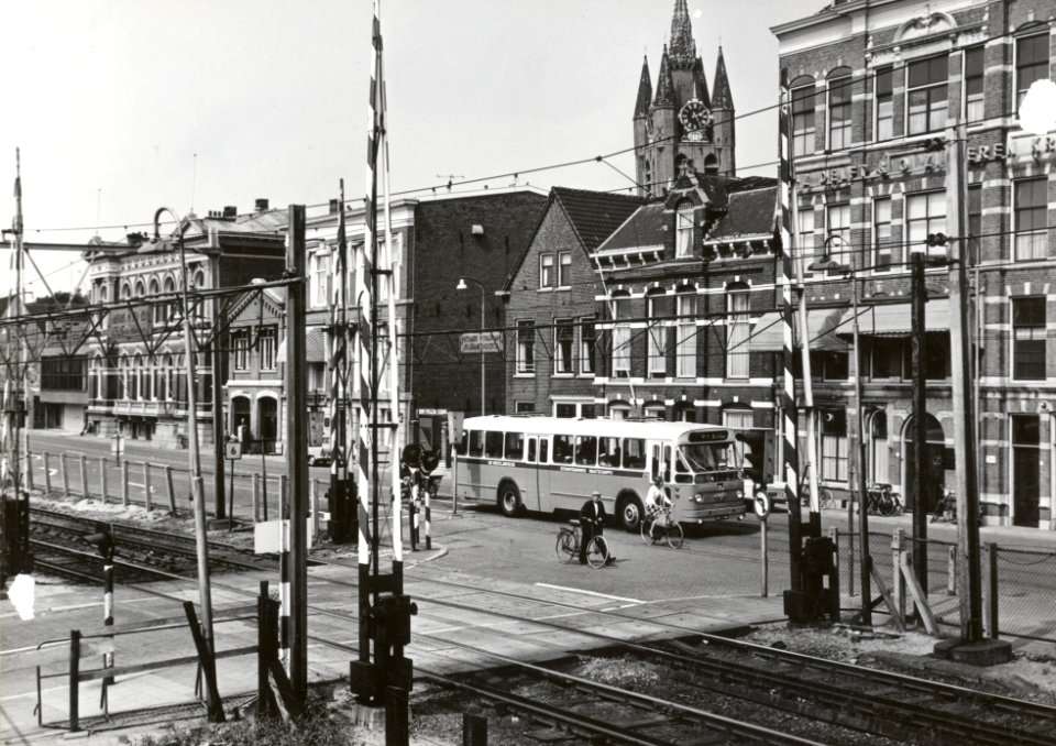 HUA-169389-Gezicht op de spoorwegovergang tussen de Spoorsingel en de Phoenixstraat (achtergrond) te Delft, met een autobus van de N.V. Westlandsche Stoomtramweg Maatschappij