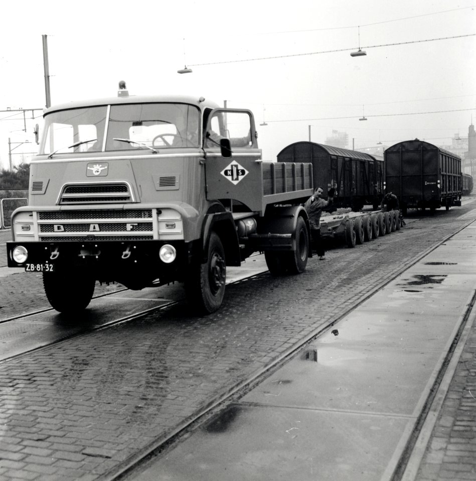 HUA-168104-Afbeelding van het vervoer van een goederenwagen van de NS op een oplegger van een vrachtauto wagon trailer of rolwagenvervoer te Eindhoven