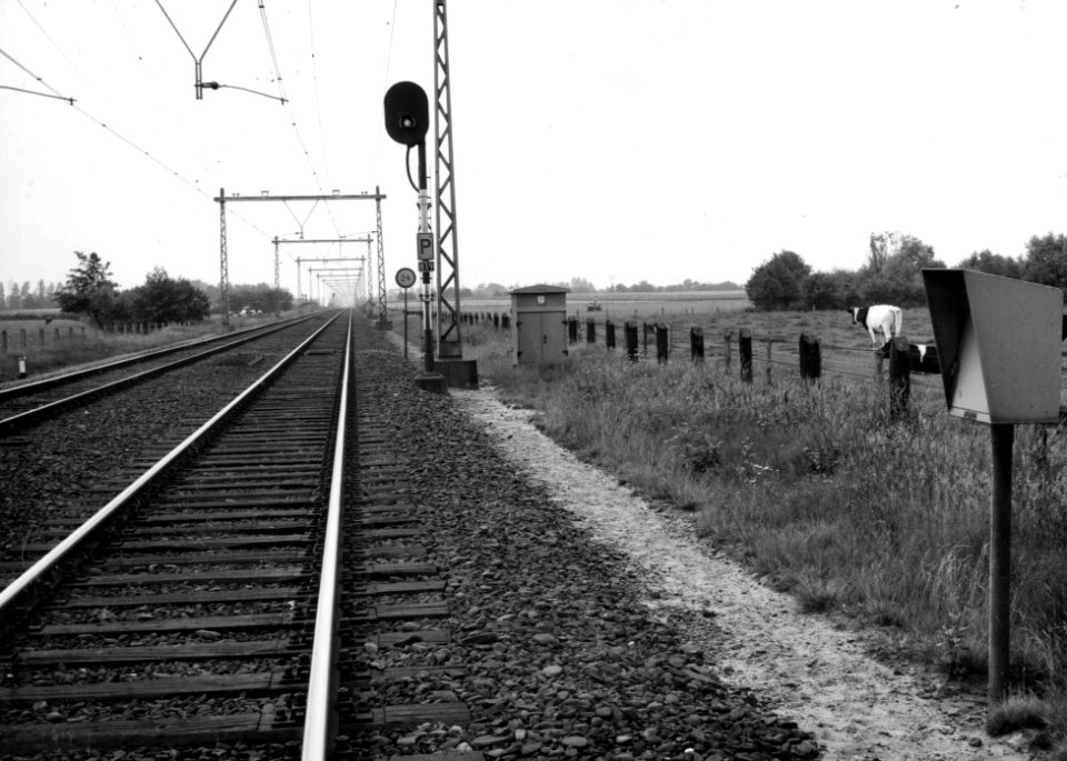 HUA-169488-Gezicht op de spoorlijn tussen Nijkerk en Amersfoort, met bakens en een voorsein ter hoogte van km. 25.4, uit het noordoosten. Rechts een telefoonkast