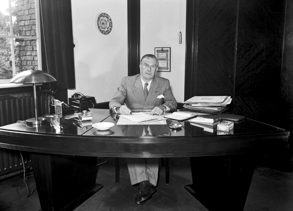 HUA-165721-Portret van dr ir FQ den Hollander 1893 1982 president directeur van de NS van 1947 tot 1958 gezeten achter zijn bureau in het 3e Administratiegebouw 