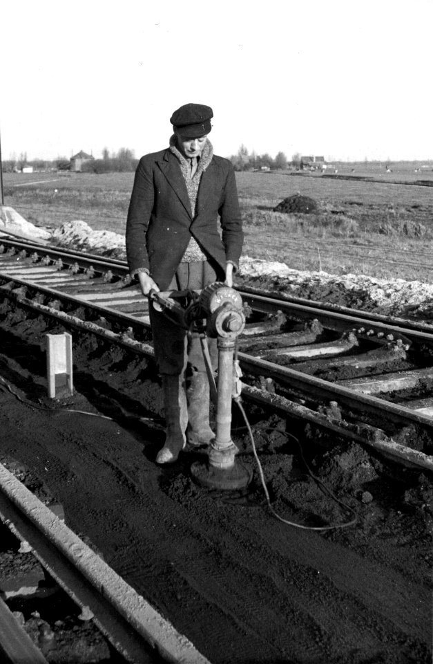 HUA-165746-Afbeelding van een wegwerker van de N.S. tijdens het aantrillen van de grond in verband met de baanverzwaring tussen Gouda en Oudewater