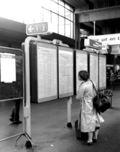 HUA-166120-Afbeelding van een reizigster bij het vertrektijdenbord in de stationshal van het N.S.-station Utrecht C.S. te Utrecht