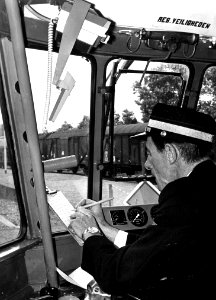 HUA-167808-Afbeelding van een machinist van de N.S. in de cabine van een diesel-electrisch treinstel DE 2 ("Blauwe Engel") tijdens het noteren van de van de radioverkeersleider ontvangen opdrachten op het ritbla