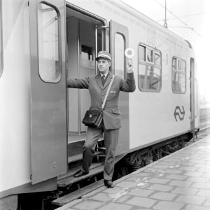 HUA-167732-Afbeelding van een conducteur tijdens het geven van het vertreksein voor een trein op het N.S.-station Utrecht C.S. te Utrecht
