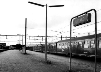 HUA-153268-Gezicht op het perron van het N.S.-station Sittard te Sittard. Langs het perron staat een trein bestaande uit rijtuigen plan W en plan E