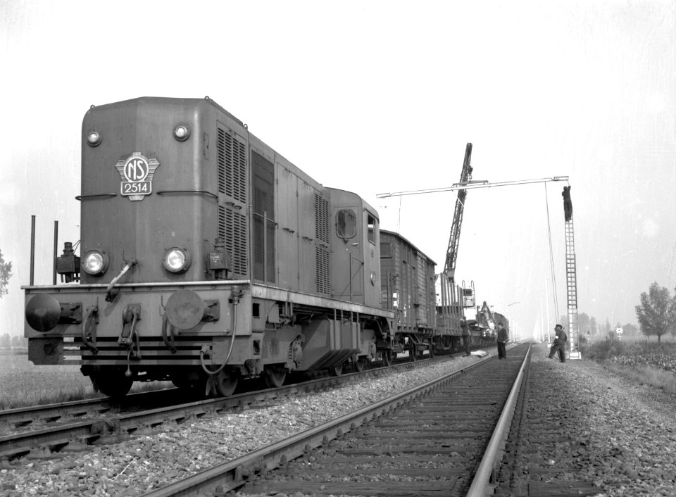 HUA-166443-Afbeelding van een werktrein met de diesel-electrische locomotief nr. 2514 (serie 2400-2500) van de N.S. tussen Roosendaal en Essen, tijdens het plaatsen van bovenleidingsportalen in verband met de el