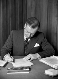 HUA-165720-Portret van dr. ir. F.Q. den Hollander (1893-1982), president-directeur van de N.S. van 1947 tot 1958, gezeten achter zijn bureau in het 3e Administratiegebouw van de Nederlandse Spoorwegen (HGB III, 