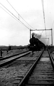 HUA-164253-Gezicht op de werkzaamheden ten behoeve van de baanverzwaring tussen Oudewater en Gouda, met een passerende trein getrokken door een stoomlocomotief uit de serie 3700-3800 van de N.S