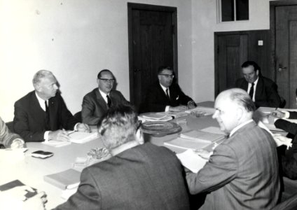 HUA-169344-Groepsportret van de concernleiding van de N.S. tijdens een vergadering, met van links naar rechts mr. W.J. de Graaff, mr. P.R. Leopold, mr. L.W. Wansink en ir. H. Zeydner. Op de voorgrond (op de rug 